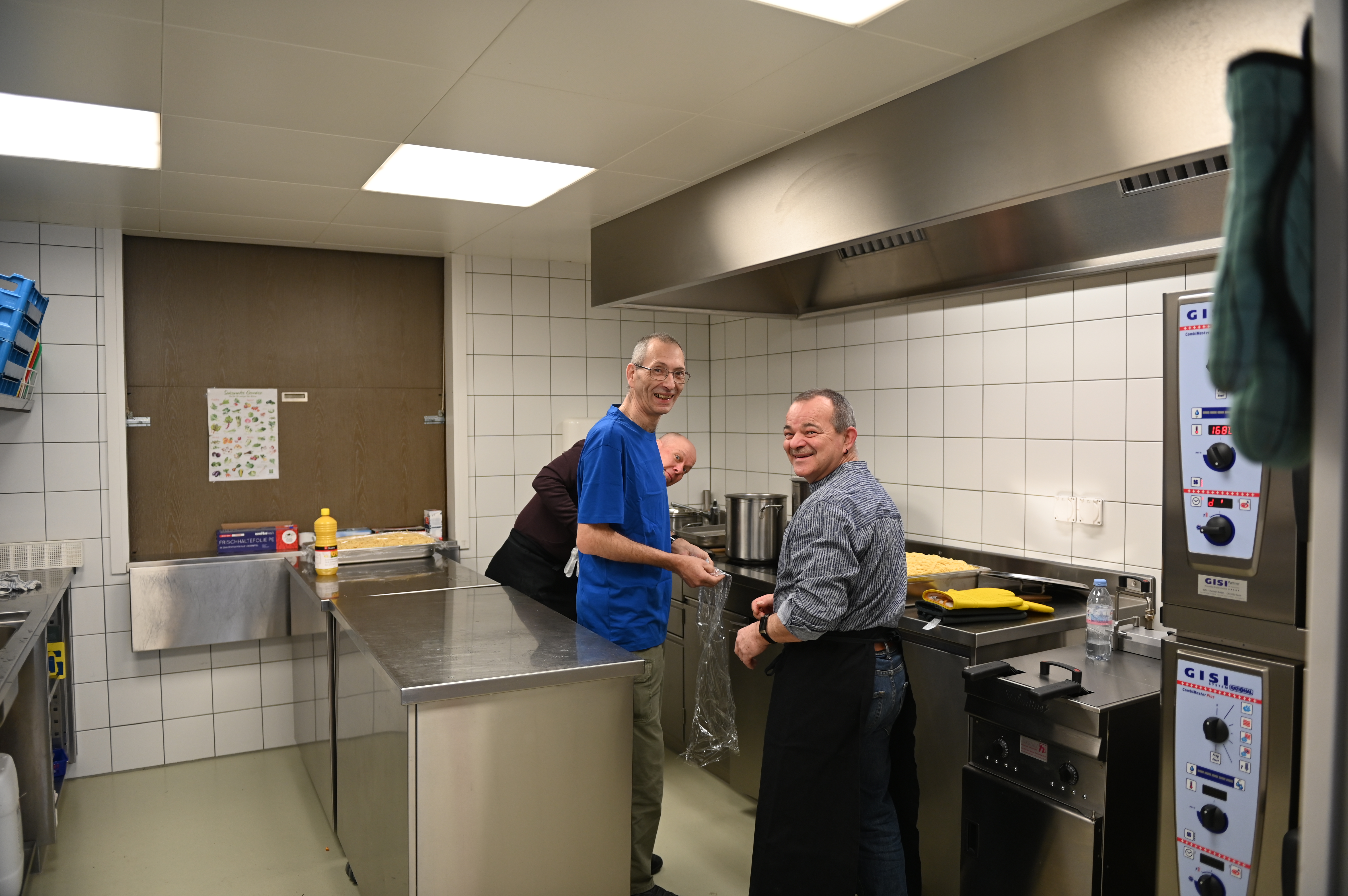Drei Küchenchefs in der Küche der Mehrzweckanlage am Spaghetti-Kochen.